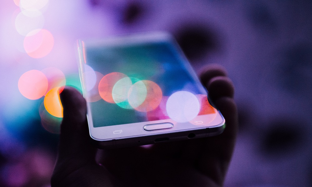 A shaded hand holding a smartphone.