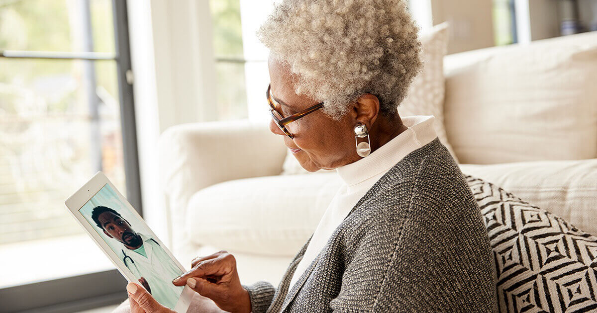 A woman using a tablet to visit with a doctor.