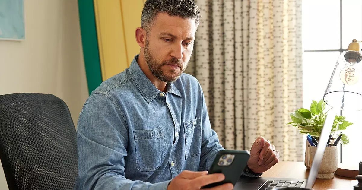 A man checking his smartphone at a desk.