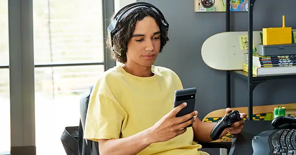 A boy using a smartphone while playing video games.